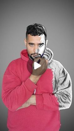 a man in a red hoodie with his hands on his chest, holding a cell phone to his mouth