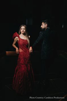 a man standing next to a woman in a red dress