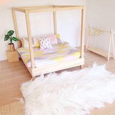 a bedroom with a bed and white fur rugs on the wooden floor next to a potted plant