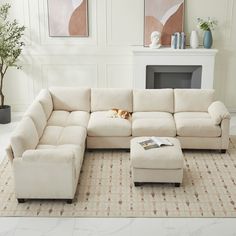 a living room with a large sectional couch and footstool in front of a fireplace