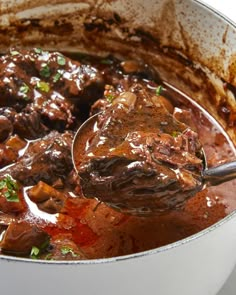 a pot full of stew with a spoon sticking out of it's meat and vegetables