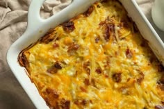 a casserole dish with cheese and meat in it on a table next to a cup