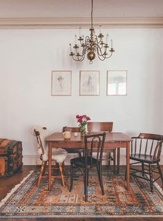 a dining room table with four chairs and a rug on the floor in front of it