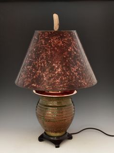 a lamp with a brown shade on it and a wooden stick sticking out of the top