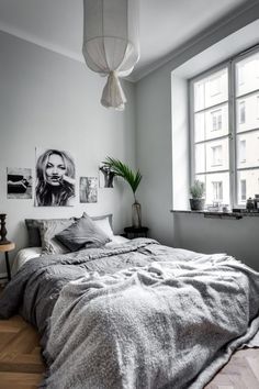 a bed sitting in a bedroom next to a window with pictures on the wall above it