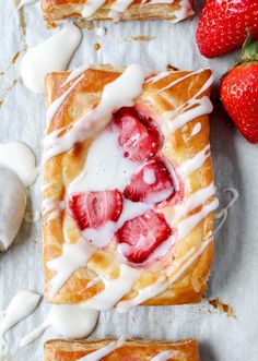 strawberries and cream are being drizzled with icing on top of pastries