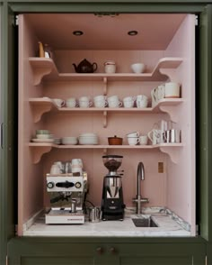 a coffee maker is sitting in the middle of a shelf filled with dishes and cups