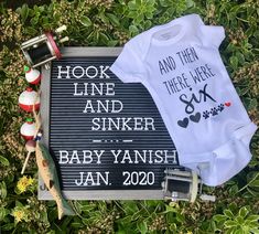 two baby onesuits sitting next to each other on top of green leaves and grass