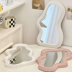 three different shaped mirrors sitting on top of a white table next to a dresser and mirror