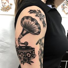 a woman with a tattoo on her arm has an old record player in it's hand