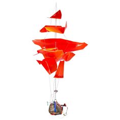 a wind chime hanging from the side of a white wall with an orange and red sailboat on it