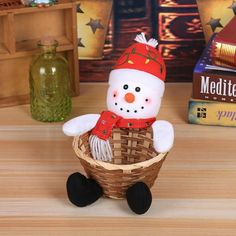 a small snowman sitting in a basket next to some books