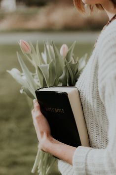 a woman holding a book with flowers in it