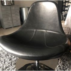 a black leather office chair sitting on top of a carpeted floor next to a dresser