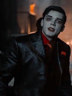 a man in a suit and tie with blood on his face standing outside at night