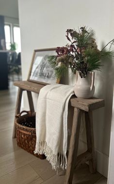 a vase filled with flowers sitting on top of a wooden table next to a mirror