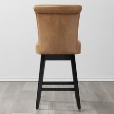 a brown leather bar stool in front of a white wall