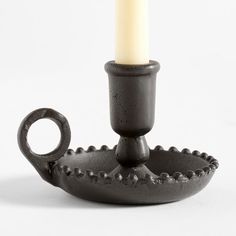 a black candle holder with a lit candle in it