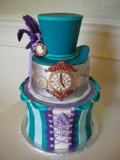 a three tiered cake decorated with purple, blue and silver ribbons and an ornate top hat