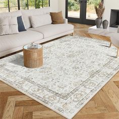 a living room with white couches and a rug on the floor in front of a large window