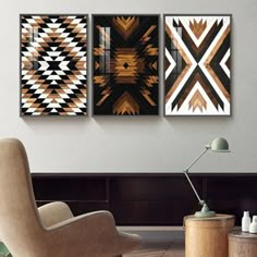 three abstract paintings hang on the wall above a chair in a living room with a coffee table