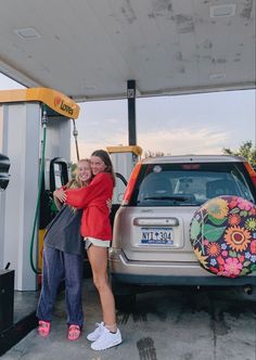 two women hugging each other in front of a gas station