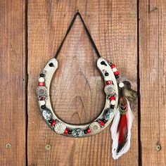 a white horseshoe with red and black beads hanging on a wooden wall next to a bird