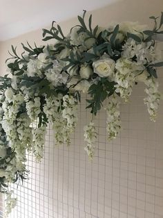 white flowers and greenery are hanging on the wall