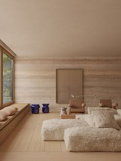 a living room filled with furniture next to a large window covered in white fluffy blankets