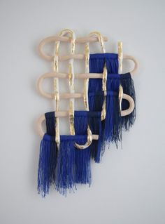 three blue and white wall hangings with metal hooks on them, each holding two different types of hair clips