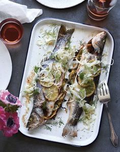 an image of fish on a tray with lemons and herbs for garnish