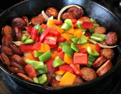 a skillet filled with sausage, peppers and onions