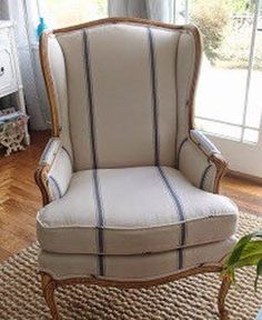 a white chair sitting on top of a wooden floor next to a potted plant