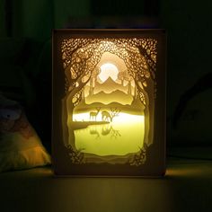 a night light with an animal scene in the middle and trees on the other side