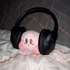 a stuffed animal with headphones laying on a bed