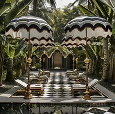 two black and white umbrellas sitting in the middle of a pool surrounded by palm trees