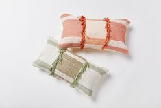 two orange and white pillows sitting next to each other on top of a white surface