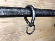 a metal hook is attached to a wooden wall with a chain hanging from it's end