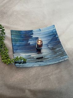 a vase sitting on top of a blue plate next to a green plant in the middle