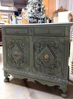 an old dresser is painted green and has ornate designs on the doors, drawers, and sides