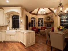 a large kitchen with white cabinets and wood flooring is pictured in this image, there are chandeliers hanging from the ceiling