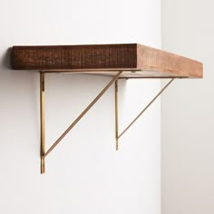 a wooden shelf with two brass brackets on it