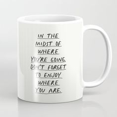 a coffee mug with the words in the midst of where you're going, don't forget to enjoy where you are