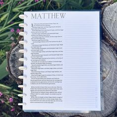 a notebook with the words mathew written on it sitting next to some wood and purple flowers