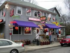 a car parked in front of a restaurant with purple awnings and neon signs