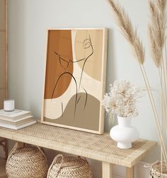 a table with baskets and vases on top of it next to a framed art piece