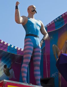 a man in striped tights standing on top of a carnival float with his hand up