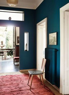 a room with blue walls and a red rug on the floor next to a radiator