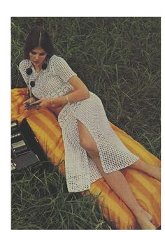 a woman laying in the grass with her legs crossed on a yellow and orange blanket