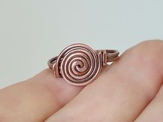 a person's hand holding a ring with a spiral design on it